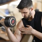 Focused man lifting dumbbell, showcasing strength and fitness indoors.