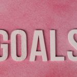 Motivational word 'GOALS' on a pink watercolor background for inspiration.